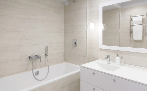Salle de bain moderne épurée avec baignoire encastrée blanche, vasque intégrée au plan de toilette blanc, robinetterie chromée murale et mitigeur lavabo
